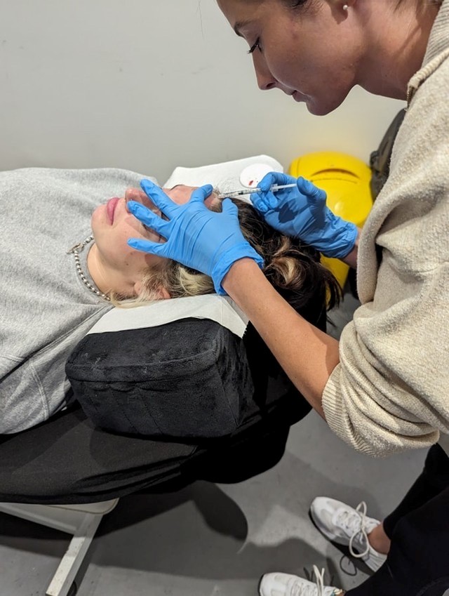 Sarah adminstering anti-wrinkle injections into a client's forehead